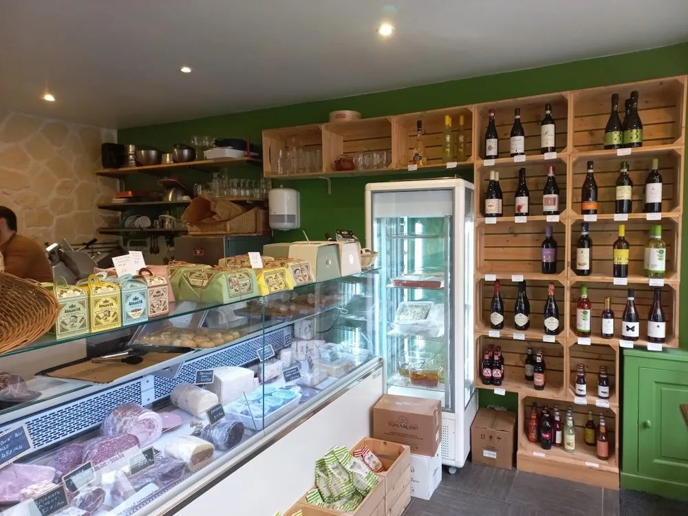 Intérieur de la boutique : vitrine de charcuteries et étagères de vins