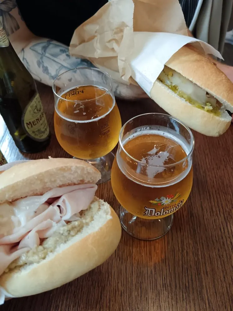 Deux panini et deux verres de bière Dolomiti sur une table